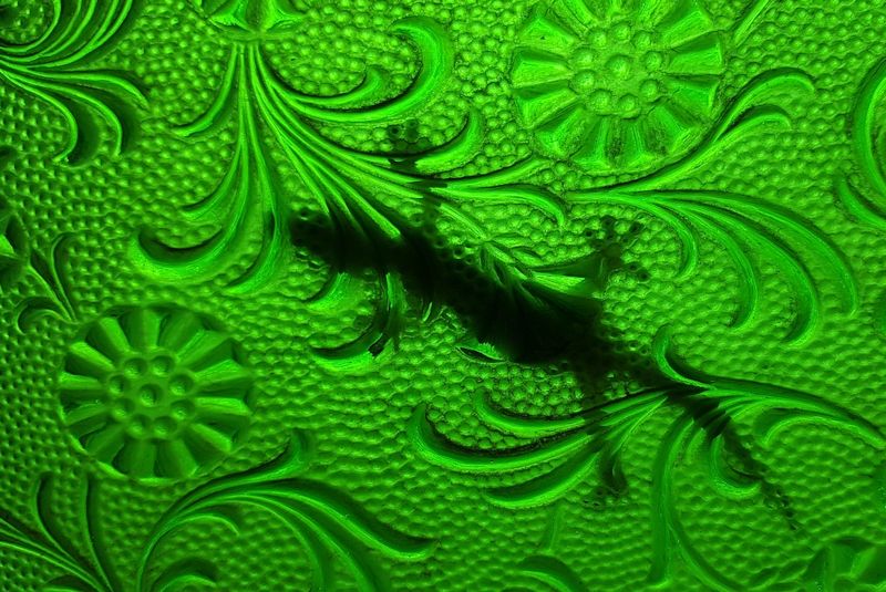 A silhouette of a gecko on decorative green glass (Xcalak)